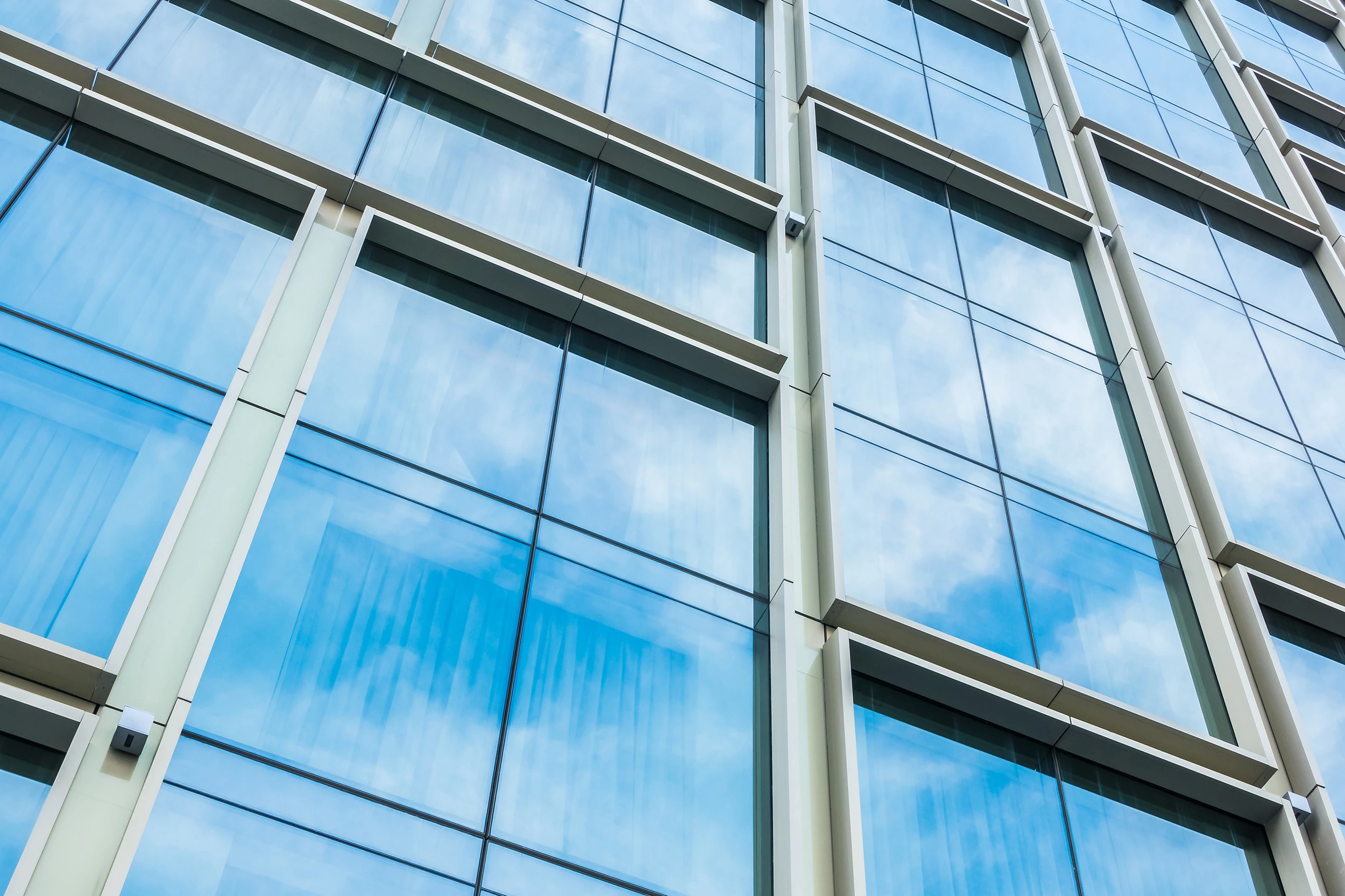 A close-up of a structural silicone glazed (SSG) curtain wall, showing the seamless glass surface